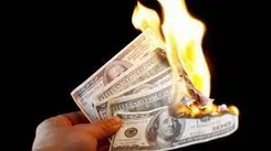 A hand holding some money that is on fire.